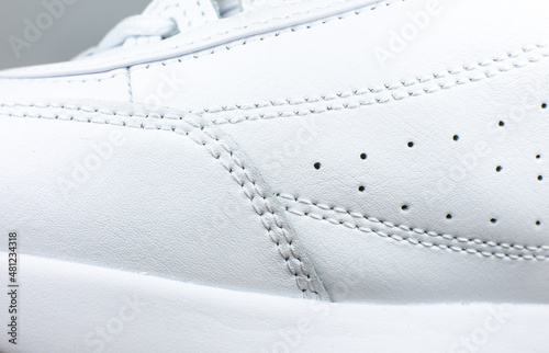 Modern sneakers background. White leather trainers. Seams Close up. Natural fabrics, textile material.