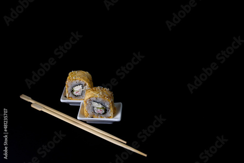 Sushi on white saucers two pieces roll chopsticks