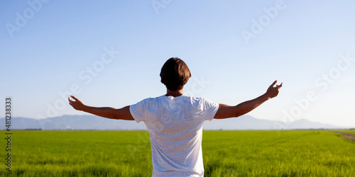 Joven con los brazos abiertos hacia el campo photo