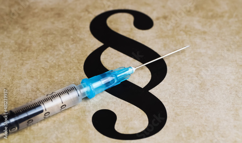 Closeup of paragraph symbol with vaccination injection syringe - mandatory vaccination concept  photo