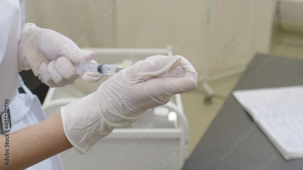 Close-up of the hands of a female doctor preparing a vaccine for injection