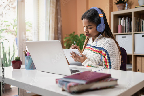 Latin American black teenager girl taking notes and studying for the University Exams at home