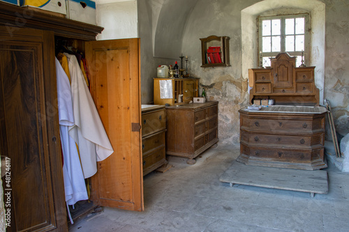 The sacristy of a country church with a old furniture and The vestments in an open cabinet. photo
