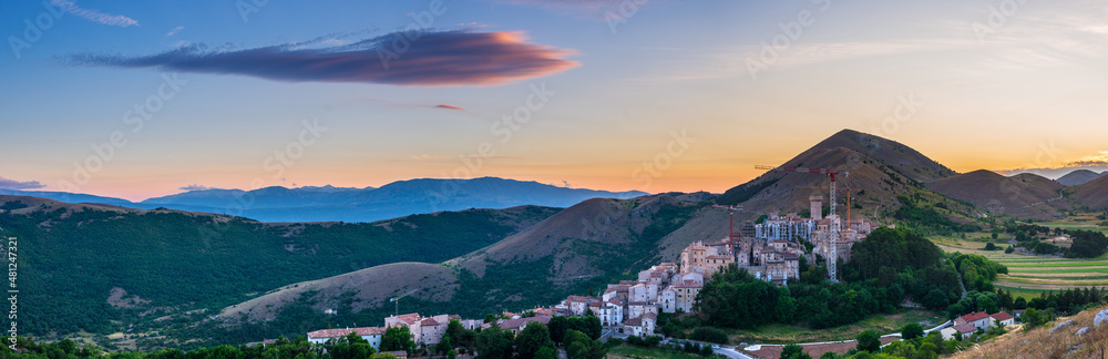 Sunset over medieval village perched on hill top, Santo Stefano di Sessanio, Abruzzo, Italy. Romantic sky and clouds above mountains landscape, tourism destination.