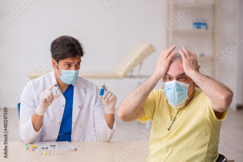 Old male patient visting young male doctor in vaccination concep photo