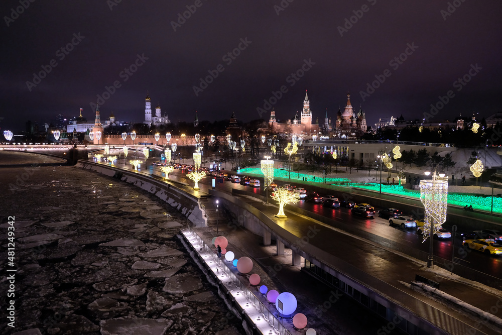 Moscow River with ice and Kremlin towers on embankment with holiday street lighting night perspective view
