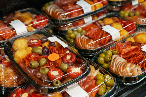Snacks in supermarket. Olives, pepperoni and stuffed tomatoes.
