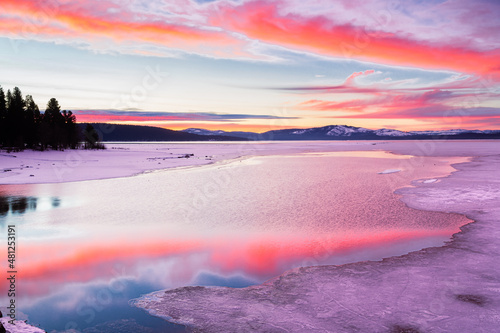 Vibrant sunrise reflecting on open water between ice.  Photographed on Lake Almanor in Plumas County, California, USA on a winter morning. photo