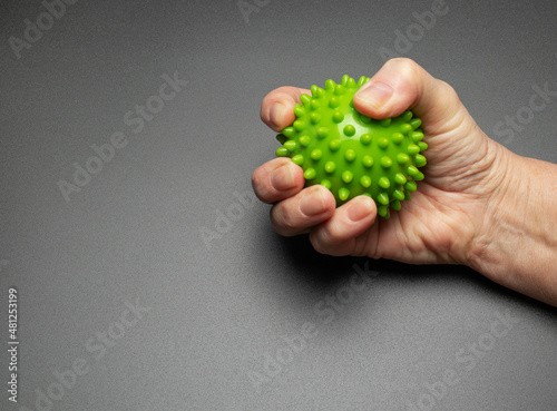 The hand of an elderly woman is squeezing a relief ball. Exercises for hands and fingers. Rehabilitation