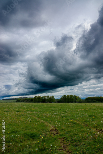 a dark black shelf cloud in a foreboding dark grey thunder storm cloud sky bringing heavy rain over open countryside