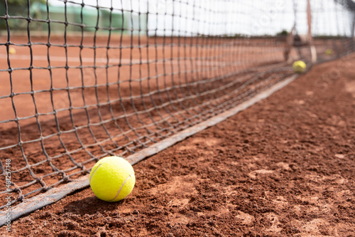 Close up on tennis ball on wet clay court near net. Sport training, tournament concepts © Josu Ozkaritz