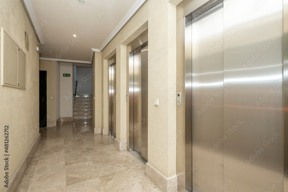 Lobby of a building with three elevators with cream marble floors Lobby of a building with three elevators with cream marble floors