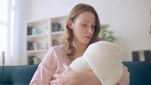 Distressed young mother rocking newborn baby, postpartum depression problem photo