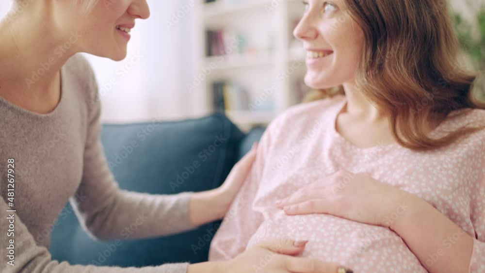 Happy lesbian couple feeling baby moving in pregnant belly, enjoying pregnancy Happy lesbian couple feeling baby moving in pregnant belly, enjoying pregnancy