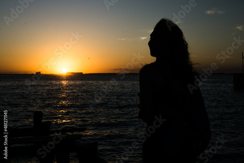 Mujer frente a atardecer en playa