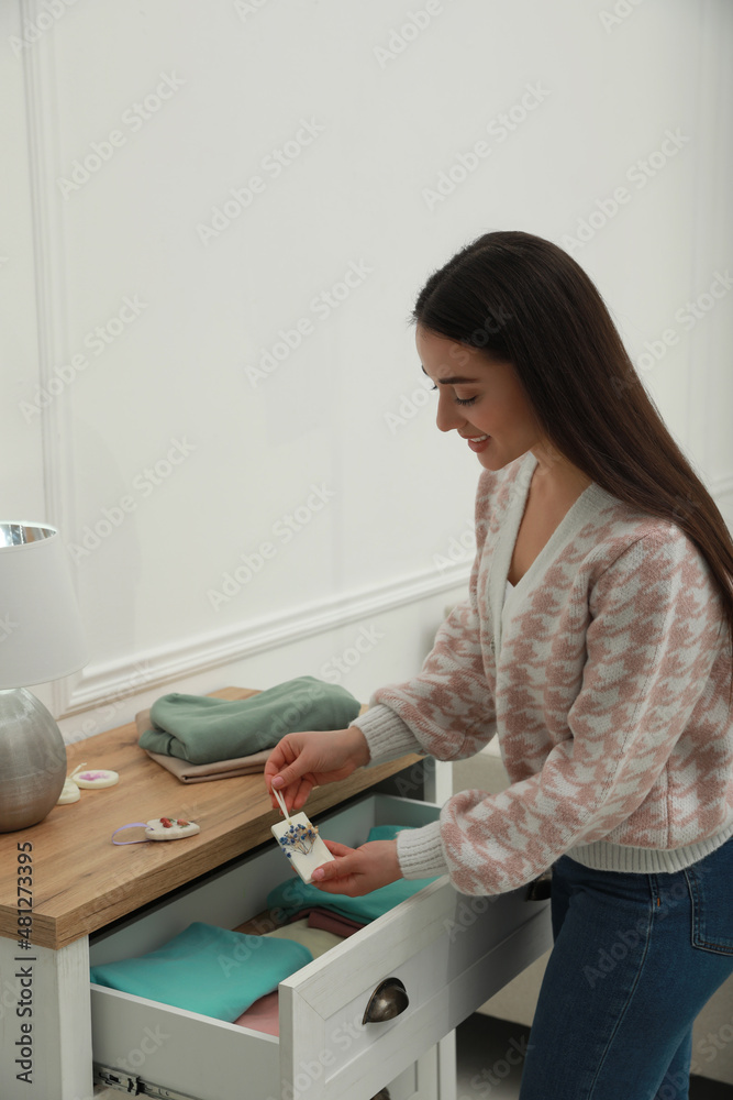 Woman putting scented sachet into drawer with clothes Woman putting scented sachet into drawer with clothes