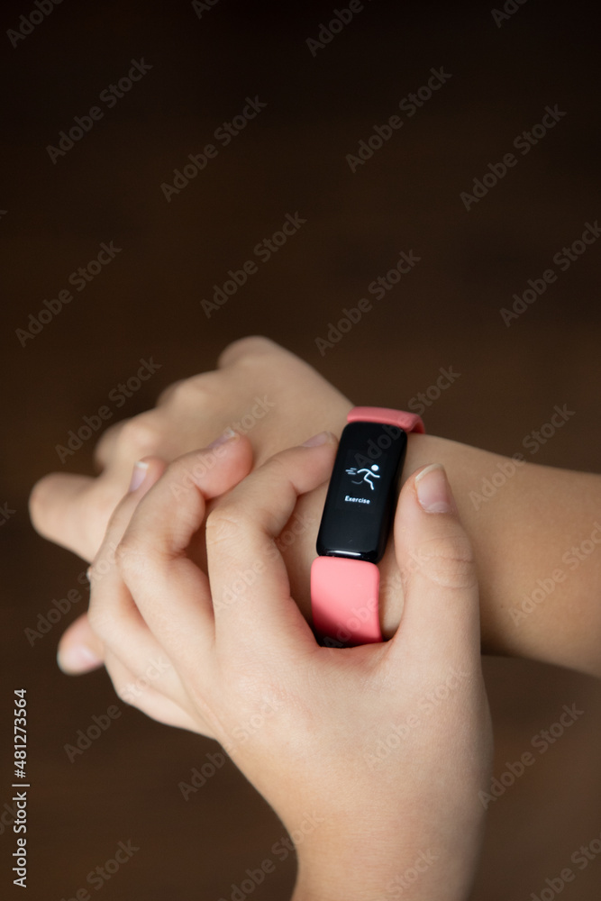 Fototapeta premium active preteen hand holding wrist smart watch exercise screen pink band