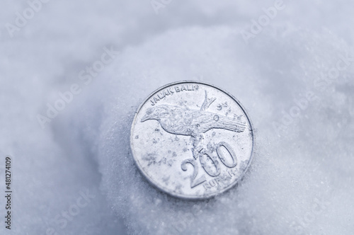 An old two hundred rupiah coin in the snow. The lost 200 rupiah coin. Money issued in 2003. Bank Indonesia. Soft focus, copy space