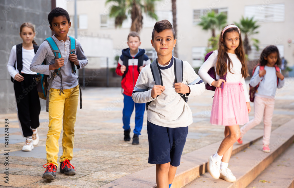 Obraz premium Portrait of preteen Hispanic boy with rucksack walking outdoors on his way to school on warm autumn day. Back to school concept.