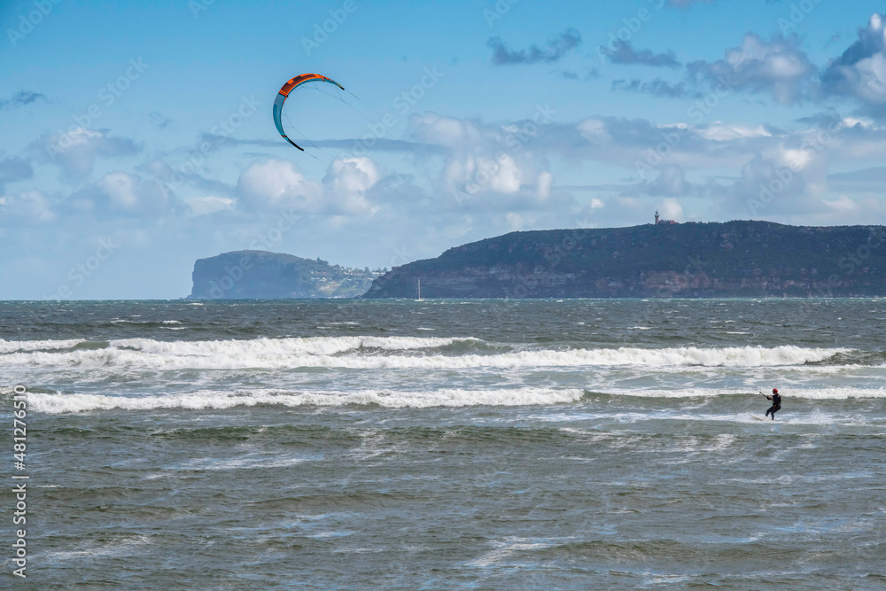 Windsurfers riding the waves on a wild day at the beach