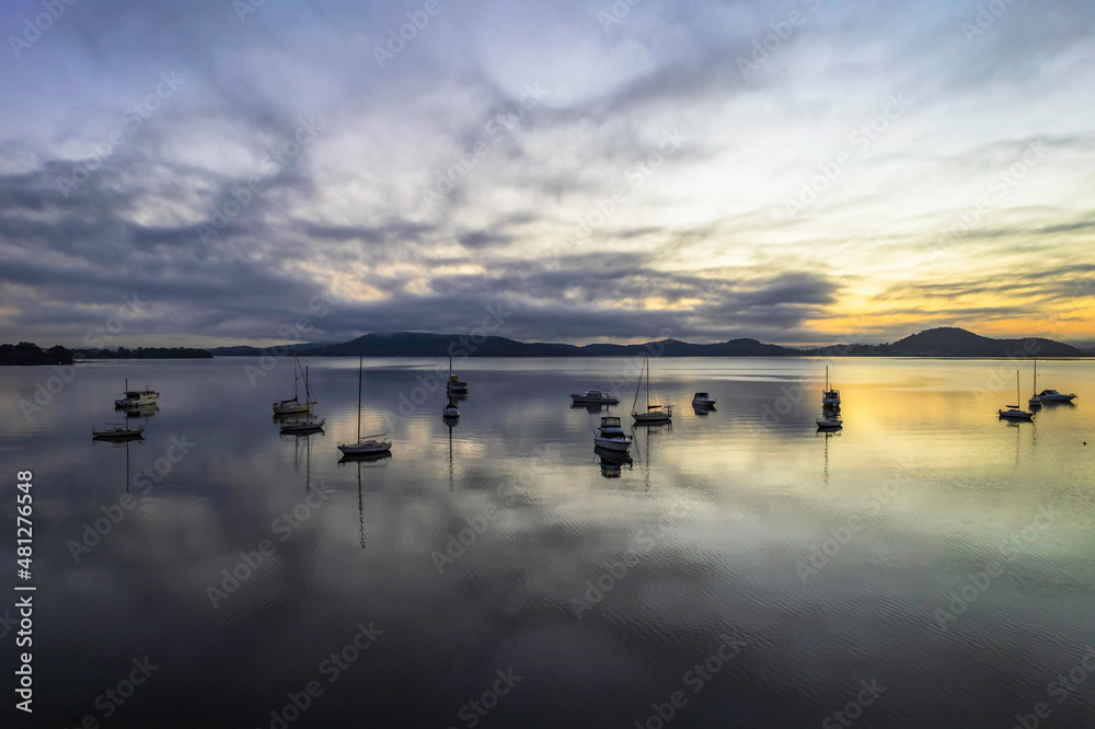 Sunrise waterscape with boats, soft clouds and reflections