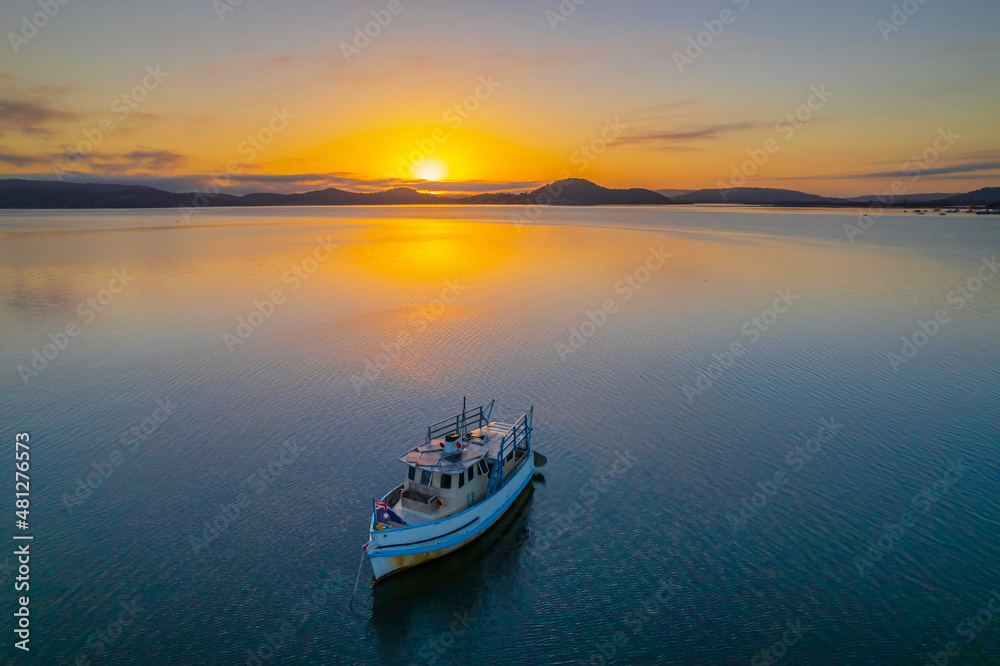 Sunrise waterscape with a boat, soft clouds and golden glow Sunrise waterscape with a boat, soft clouds and golden glow