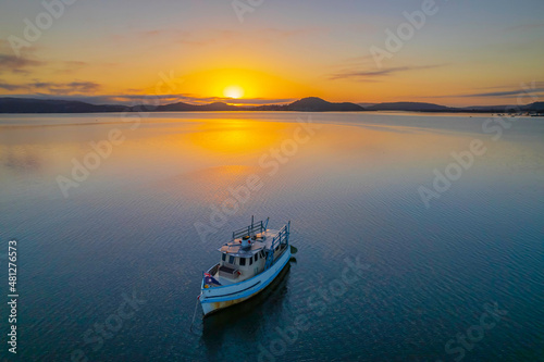 Sunrise waterscape with a boat, soft clouds and golden glow
