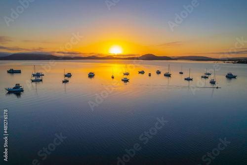 Sunrise waterscape with boats  soft clouds and reflections
