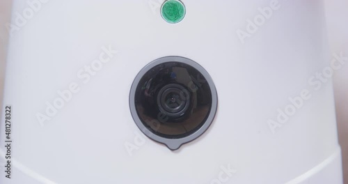 Person removes protective film from camera of new automatic pet feeder machine, close up, front view. Device for feeding domestic animals according to schedule and timer with surveillance system.