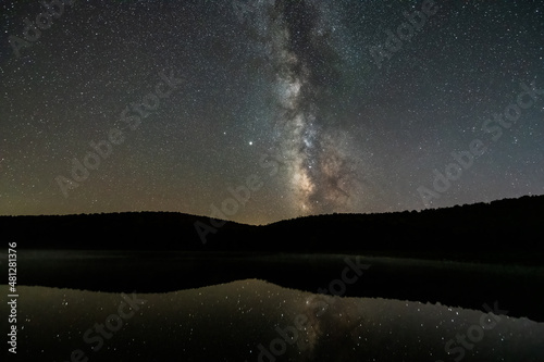 Night dark sky with milky way in Spruce Knob Lake West Virginia water reflection of stars landscape view with brightest star Sirius glowing with Venus planet