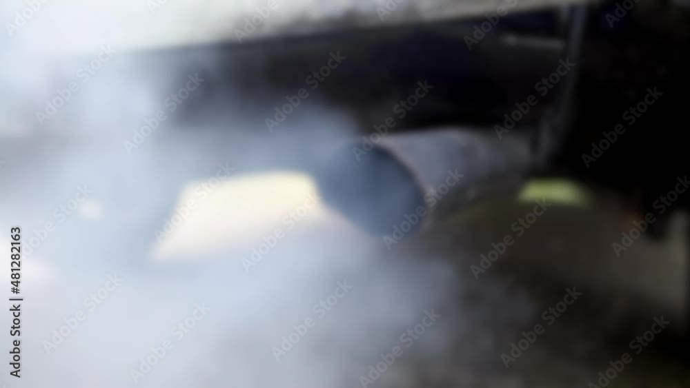 Defocused shot of combustion fumes coming out of car exhaust pipe which