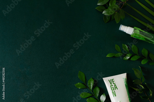 Vegan cosmetic cream isolated on deep green background. Skin care concept. photo