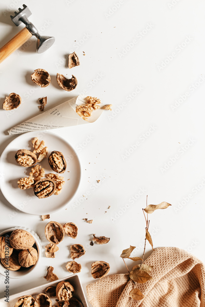 Cosy autumn aesthetic composition with dry  leaves, walnuts on white background. Flat lay, top view, copy space.