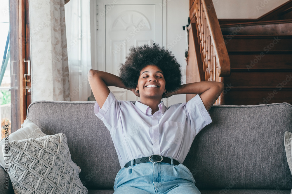 Happy african american woman sitting on sofa with eyes closed and ...