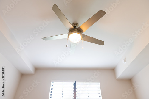Empty bedroom room interior nobody looking up low angle view at lit illuminated yellow light ceiling fan window in new modern luxury apartment home house © Andriy Blokhin