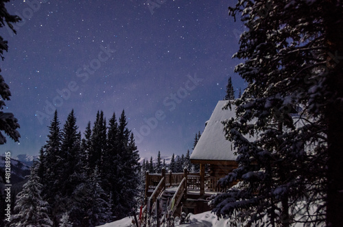 Starry skies over a cabin at night in the snowy mountains