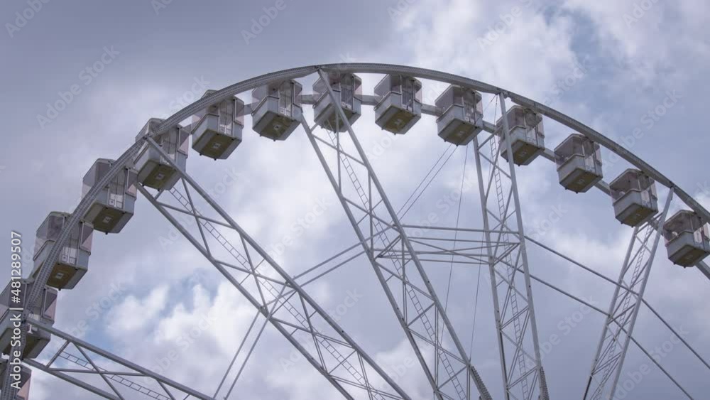 Rotating ferris wheel against the blue sky and clouds background. Slow motion, wide angle shot. Rotating ferris wheel against the blue sky and clouds background. Slow motion, wide angle shot.