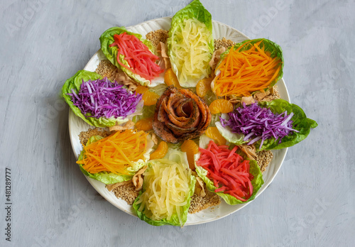 Modern Chinese fish salad. Yusheng aka Prosperity Toss. Mixed variety of vegetables ingredients with vibrant colors in lettuce leaf pods and blend of smoked salmon slices to enhanced the taste. photo