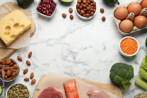 Frame with different fresh products on white marble table, flat lay. Sources of essential amino acids