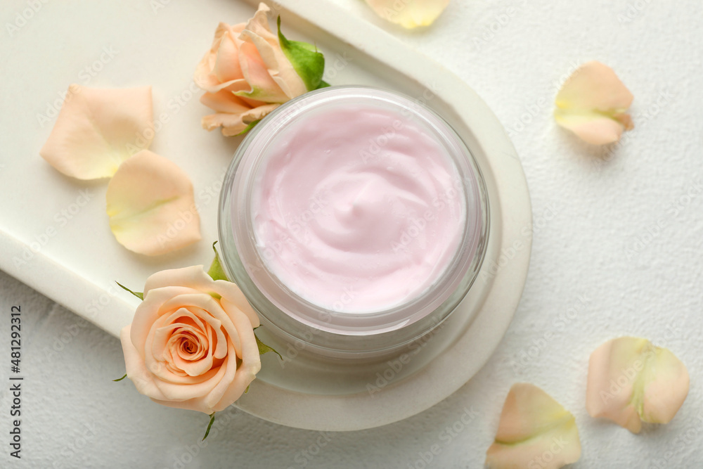 Jar of organic cream and roses on white table, flat lay