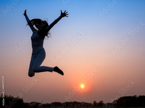 silhouette woman shadow jumping and raise hands with sunset sky background