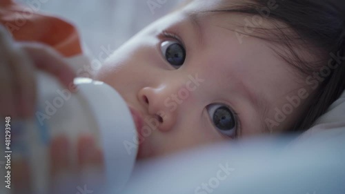 closeup baby infant blinking eyes and smile after drink milk from bottle. kid eye blink. happy smile baby face. asian child.