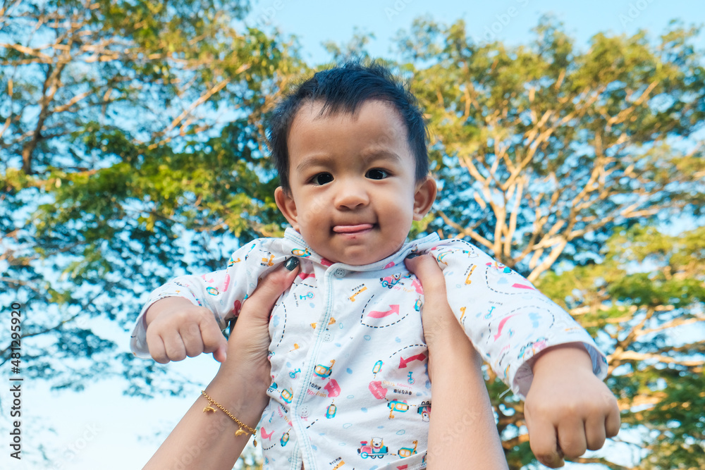 Ypung asian mother throws up her infant baby boy in the park outdoor vacation in morning Ypung asian mother throws up her infant baby boy in the park outdoor vacation in morning