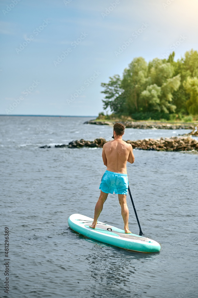 A man in blue swimming shorts with a kayak A man in blue swimming shorts with a kayak
