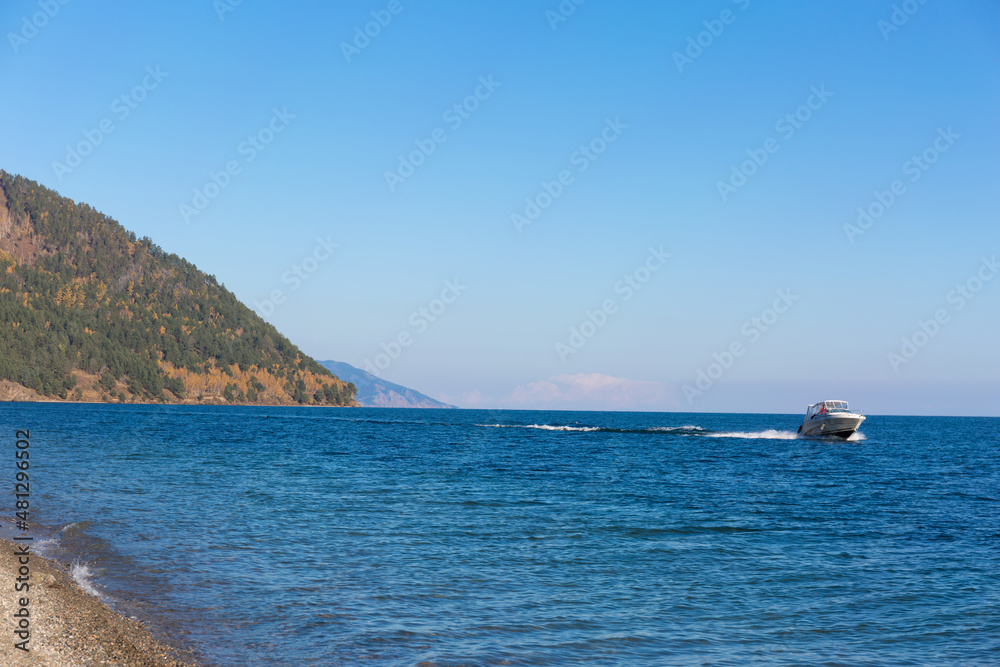 Small boat rides on the Baikal lake. Autumn landscape