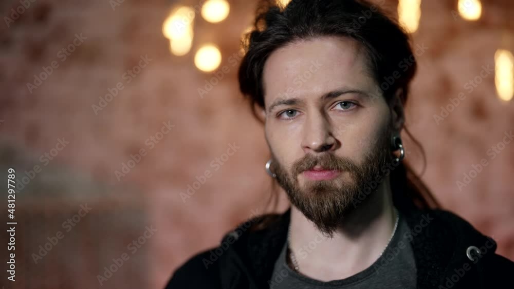 Close-up portrait of a young handsome homosexual man. Bearded brutal male face with earrings in his ears. Close-up portrait of a young handsome homosexual man. Bearded brutal male face with earrings in his ears.