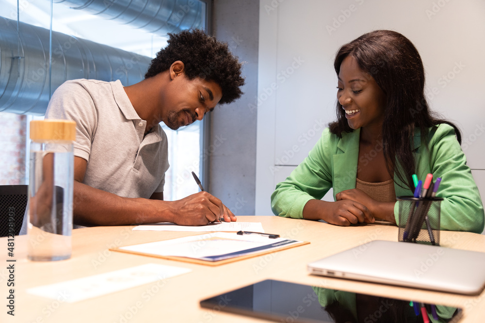 Two african american people signing contract in office. Two african american people signing contract in office.