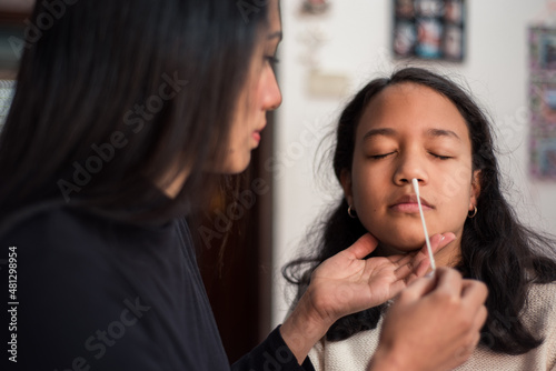 Mother ready to take a sample from her daughter's nose with the swab to perform the covid test at home. photo
