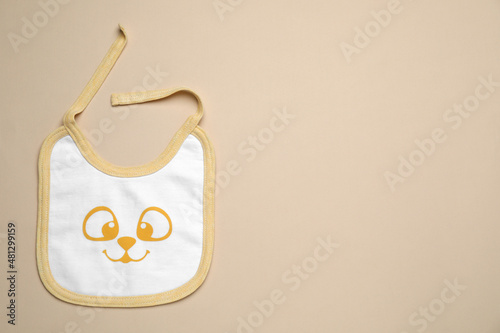 Foto New baby bib on beige background, top view. Space for text