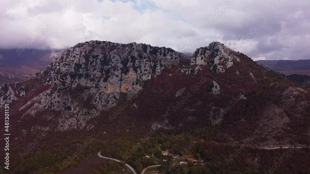 Aerial forward view of Pietroroja massif under cloudy sky. Italy. Slow motion